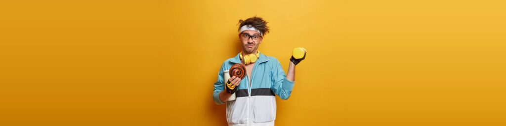 Mann im Retro-Trainingsanzug vor orangefarbenem Hintergrund mit Hantel und Handtuch