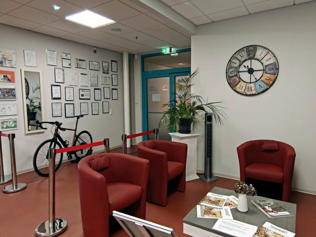 Wartebereich mit roten Sesseln, Urkundenwand und Fahrrad
