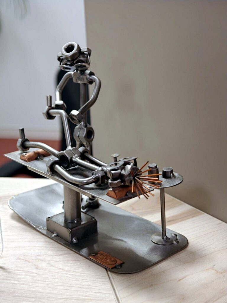 Aus Schrauben gebaute Metallfigur, die eine Übung am Gerät zeigt