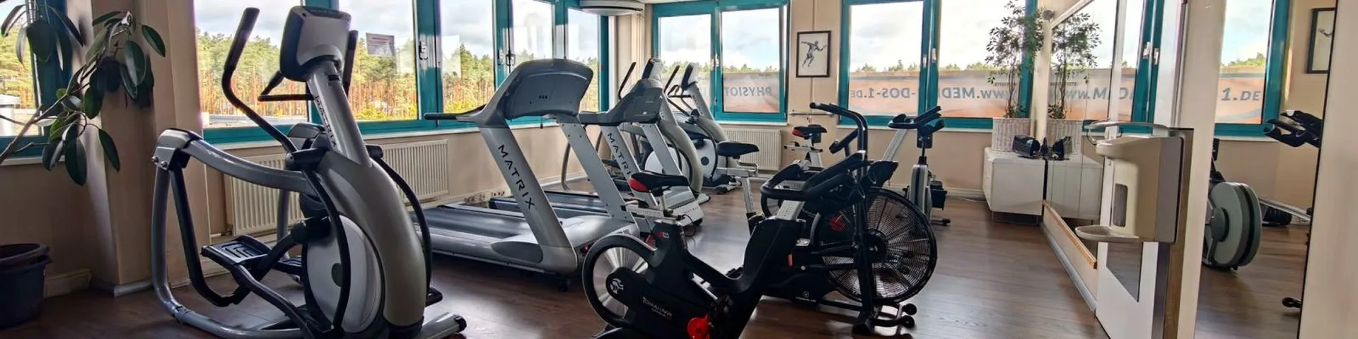 Blick über die Trainingsfläche mit Ergometern und Fensterfront